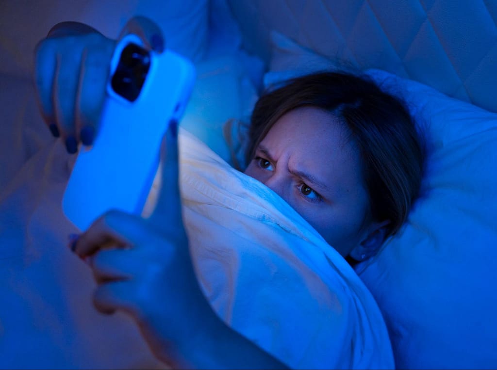 woman looking at phone in bed