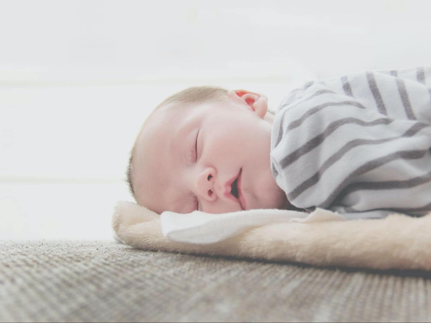 a baby sleeping on a mat